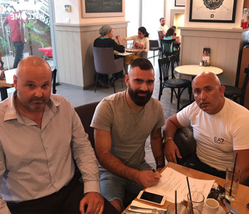 הלון יחד עם סוכנו במעמד החתימה