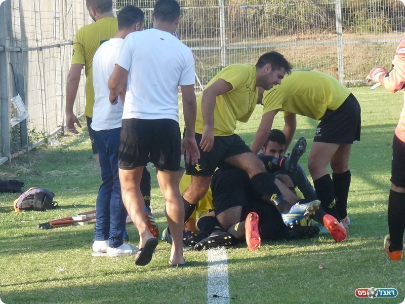 יש ערימה של חבר'ה על הדשא. שחקני השקמה בערימת שמחה על הכובש (אלי שמואלי)